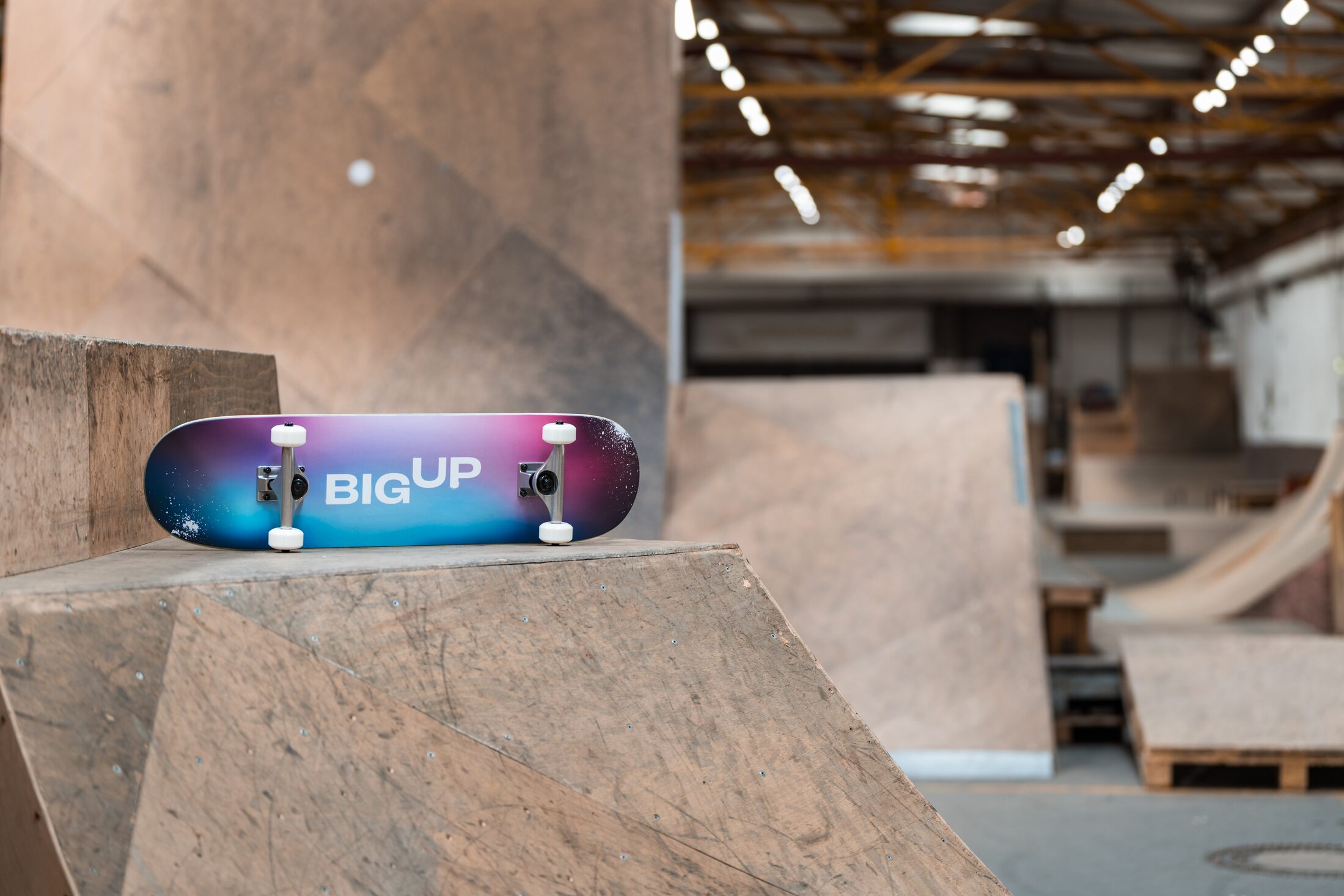 Skateboard mit der Aufschrift "BIG UP" auf einer Halfpipe in einem Skatepark