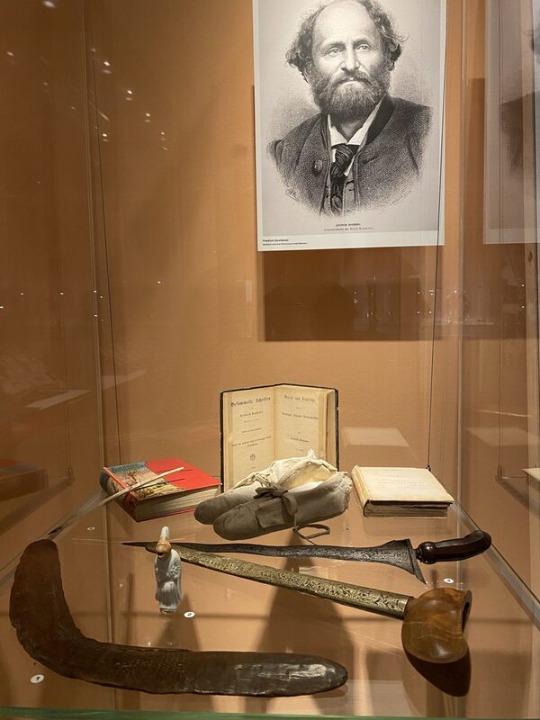 Blick in die Vitrine mit dem Bumerang in der Ausstellung „Am Anfang war der Gurt. Braunschweiger Ethnographica, Souvenirs und koloniale Trophäen“ (Wird bei Klick vergrößert)