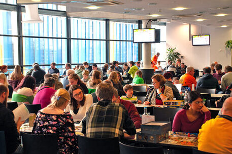 Besucherinnen und Besucher spielen an verschiedenen Tischen