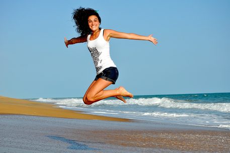 Junge Frau am Strand springt hoch