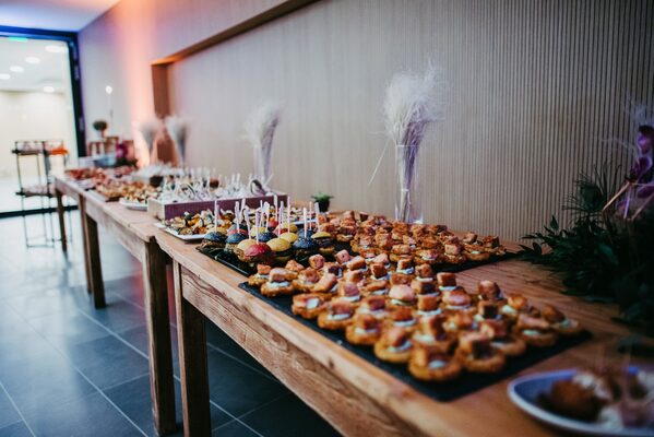 Fingerfood und Häppchen angerichtet auf langen Holztischen