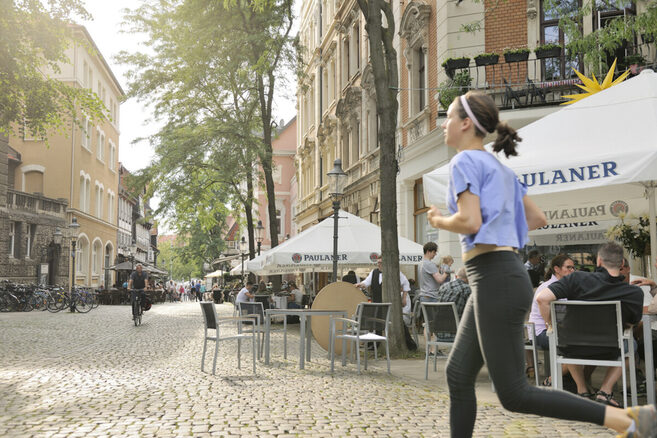 Eine Joggerin in der Innenstadt vor Cafés. (Wird bei Klick vergrößert)