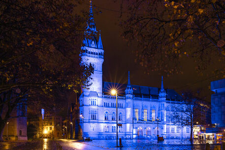 Das Bild zeigt das blau beleuchtete Rathaus.